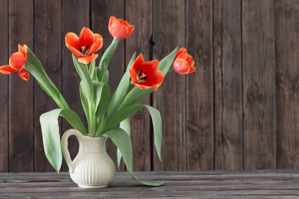 Tulips in vase on dark wooden background — Stock Photo, Image