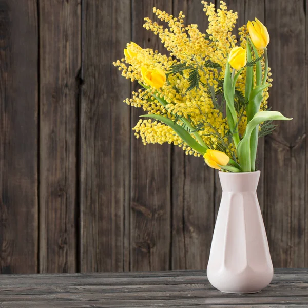 Tulipanes y mimosa en jarrón sobre fondo de madera oscura —  Fotos de Stock