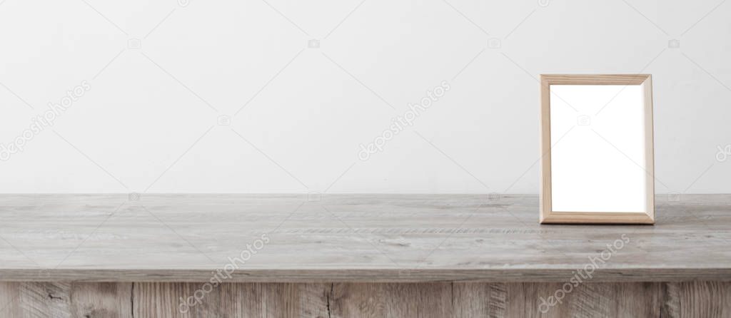 wooden frame on wooden table on background white wall