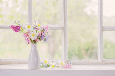 Beyaz vazodaki bahar çiçekleri eski pencere eşiğinde