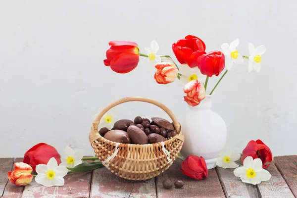 籠の中のイースターチョコレートの卵と古い木の春の花 — ストック写真
