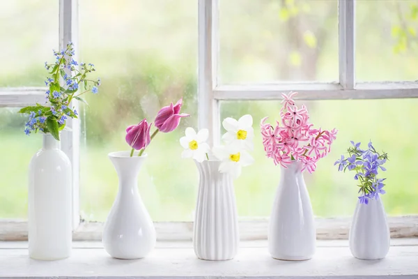 Spring flowers in white vase on old windowsill — Stock Photo, Image