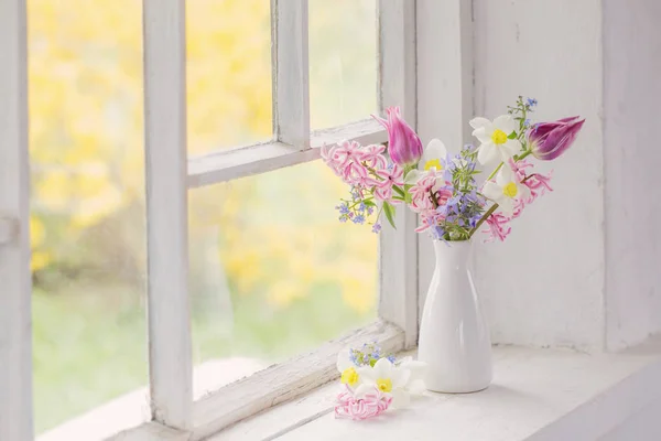 Lentebloemen in witte vaas op oude vensterbank — Stockfoto