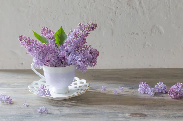 瓷杯中的一束紫丁香在旧木桌上 — 图库照片