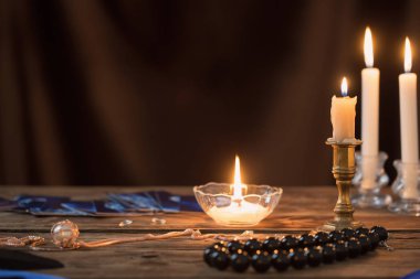 fortune-telling cards and burning candles on a wooden table on  
