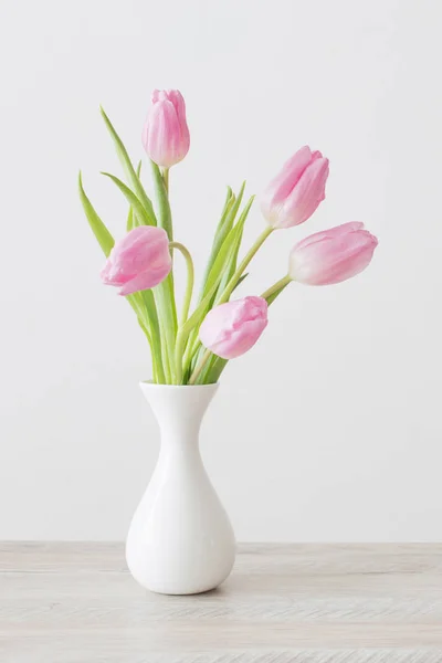 Tulipas rosa em vaso de cerâmica branca em mesa de madeira no fundo — Fotografia de Stock