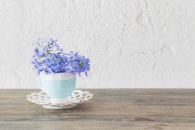 Tahta masada fincanda menekşe.