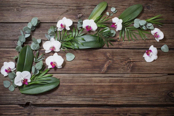Hermosas orquídeas y hojas tropicales sobre fondo de madera viejo —  Fotos de Stock