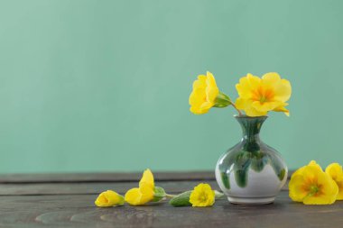 Tahta masadaki vazoda sarı çuha çiçekleri.  