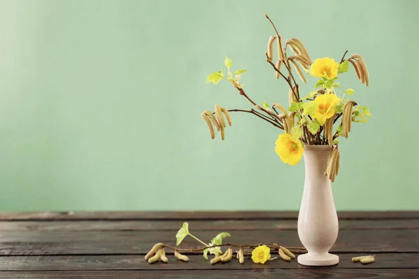spring branches and flowers  in vase on green background