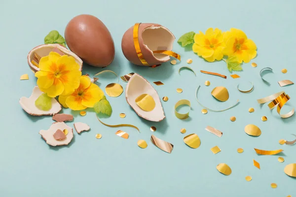 Velikonoční čokoládové vejce se zlatými konfetami a jarními květy na — Stock fotografie