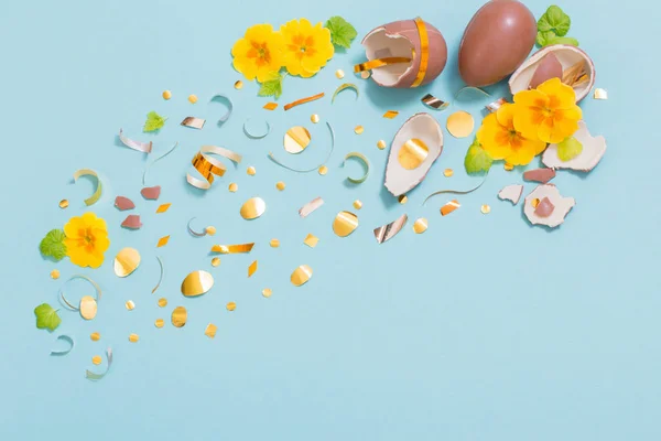 Velikonoční čokoládové vejce se zlatými konfetami a jarními květy na — Stock fotografie