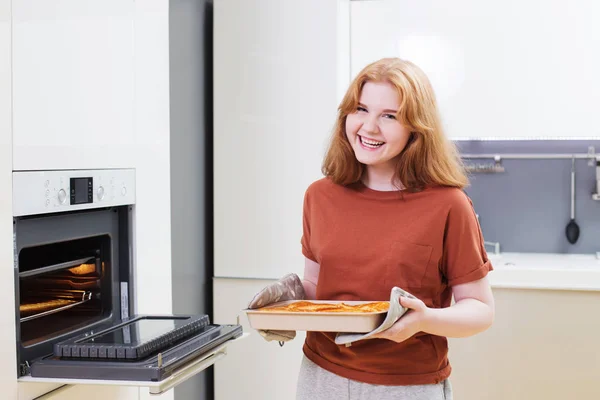 Χαρούμενο κορίτσι φτιάχνει πίτα σε μοντέρνο λευκό kithen — Φωτογραφία Αρχείου