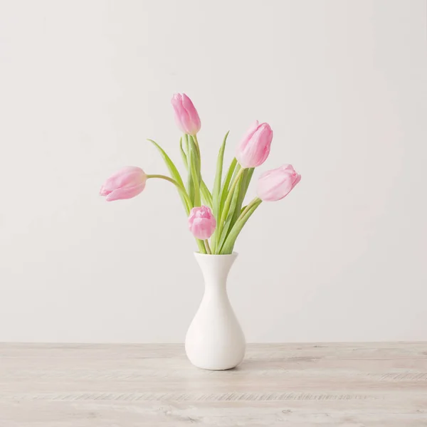 Pink tulips in white ceramic vase on wooden table on background — 스톡 사진