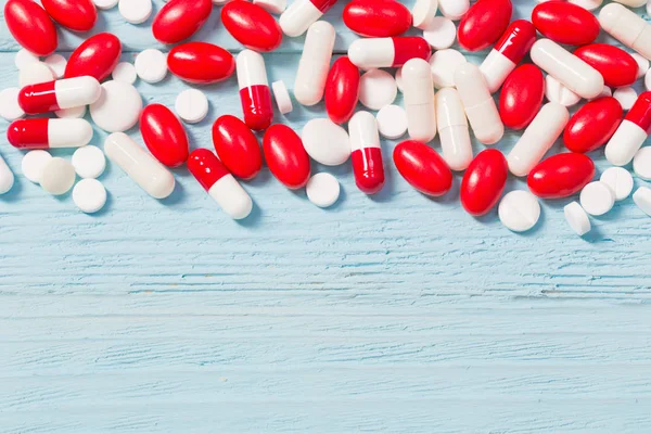 red and white pills on wooden background