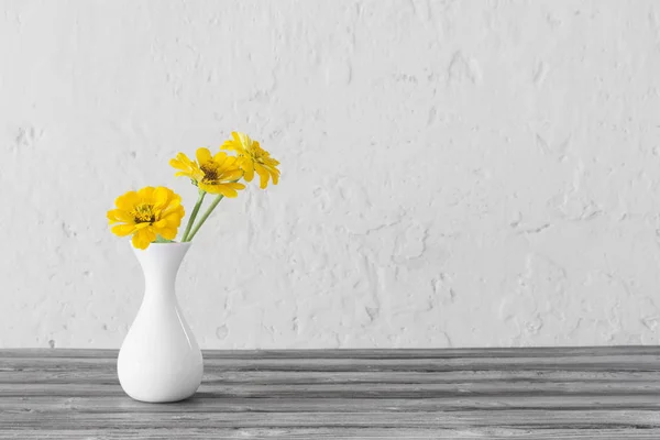 Yellow zinnia in white vase on wooden table — Stock Photo, Image