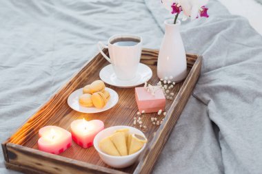 Kahve, şekerler, mumlar, çiçekler ve yatakta ahşap tepside korse. Sevgililer Günü kavramı