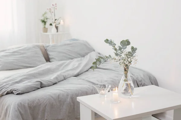 stock image burning candles and eucalyptus in glass vase in white bedroom