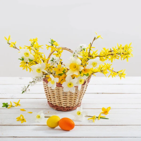 白い木製のテーブルの上に春の花とイースターの卵 — ストック写真