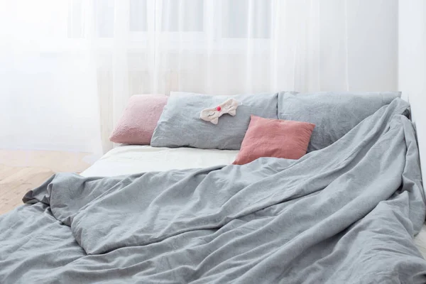 bed with gray linens and sleep mask   in white interior