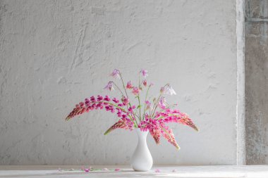 Beyaz arka planda beyaz vazoda pembe yaz çiçekleri