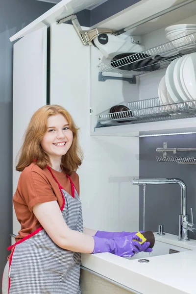 穿着紫色橡胶手套的少女在厨房洗碗 — 图库照片