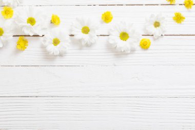 Beyaz ahşap arka planda beyaz kasımpatı ve sarı tay ayağı