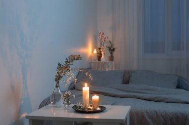 Yatak odasının içi çiçekler ve yanan mumlarla dolu.