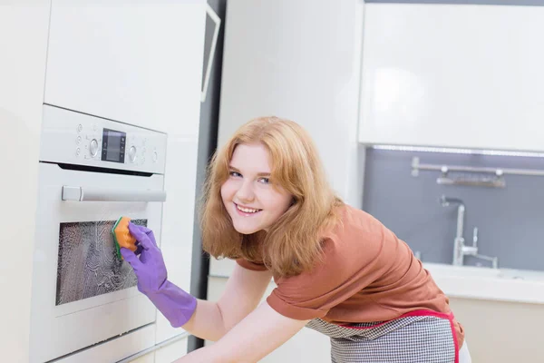 在现代厨房里 穿着紫色手套的女孩用海绵烤箱 — 图库照片