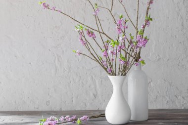 Vazodaki Daphne çiçekleri arka plandaki eski ahşap masada beyaz w