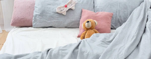 躺在灰色亚麻布上的泰迪熊床上 — 图库照片