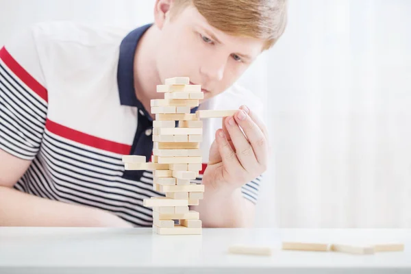 Young Man Builds Tower Wooden Cubes — Stock Photo, Image