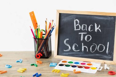 Tahtada yazı ve okul malzemeleri var. Tahta masa, okula dönüş konsepti.