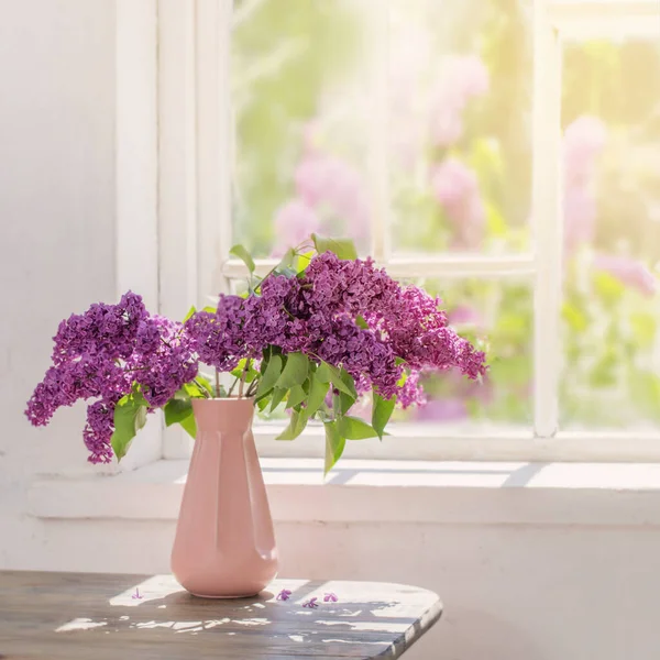 purple lilac in vase against the window on a sunny day