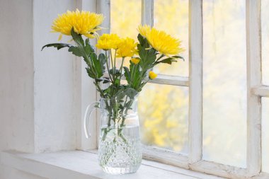 Günbatımında beyaz pencere eşiğinde sarı çiçekler