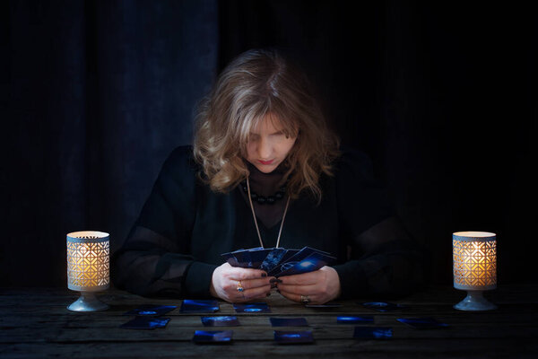 mature woman guessing with cards on dark background