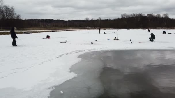 Anglers fishing on ice from drilled holes on a winter day — Stock Footage Anglers fishing on ice from drilled holes on a winter day Royalty Free Stock Video