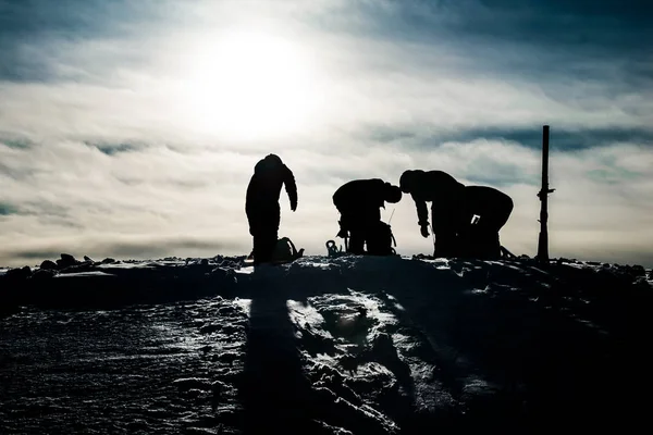 Siluetas de cuatro snowboarders preparándose para montar en la cima de la montaña — Foto de Stock