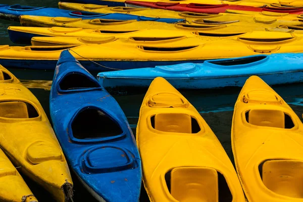 Many yellow, red and blue ocean kayaks on the pier. Abstract  background