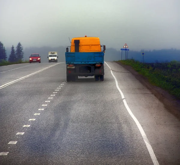 Lorry on highway-delivery of goods in bad weather threat. photo from the cab of a large truck on top — Stock Photo, Image