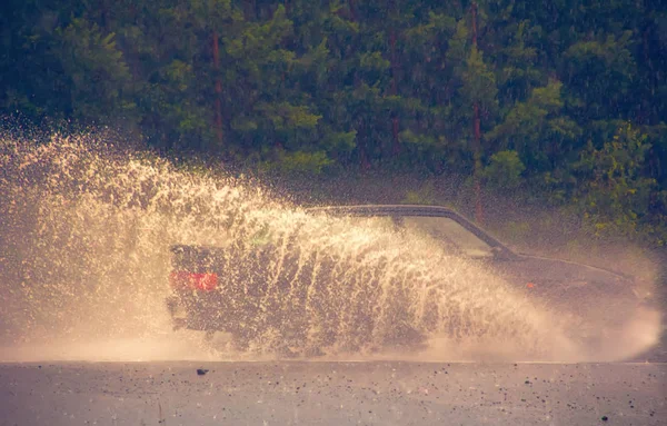 Movimiento coche lluvia gran charco de spray de agua — Foto de Stock