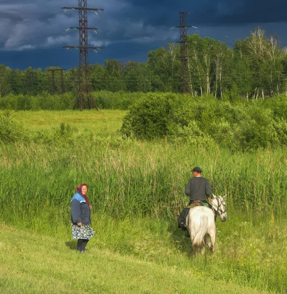 Pictures of the rural life of a man on a horse near the village — Stock Photo, Image