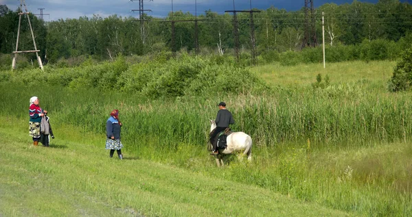 Pictures of the rural life of a man on a horse near the village — Stock Photo, Image