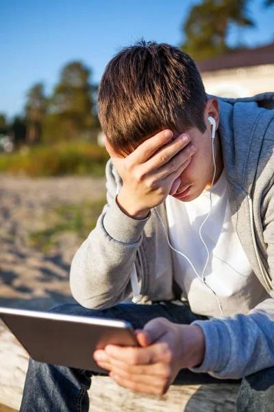 Trauriger junger Mann mit Tablette — Stockfoto