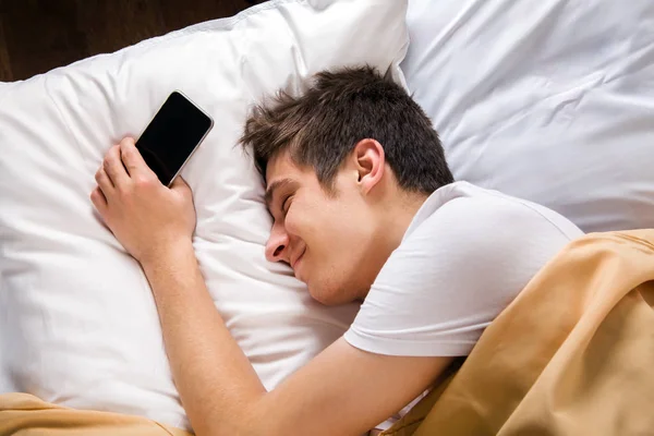 Jongeman slapen met een telefoon — Stockfoto