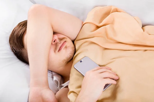 Junger Mann schläft mit einem Handy — Stockfoto