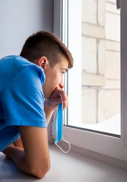 Joven Pensativo Junto Ventana Sostiene Una Máscara Contra Gripe — Foto de Stock