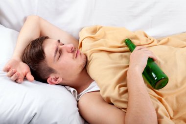 Bir bira şişesi evde yatakta yatmak genç adam
