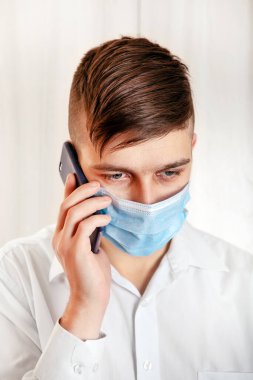 Grip Maskeli Genç Adam Duvar kenarında cep telefonu olan.