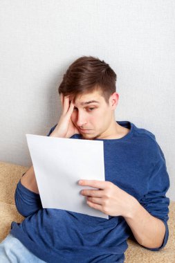 Üzgün genç adam evdeki koltukta bir belge okudu.